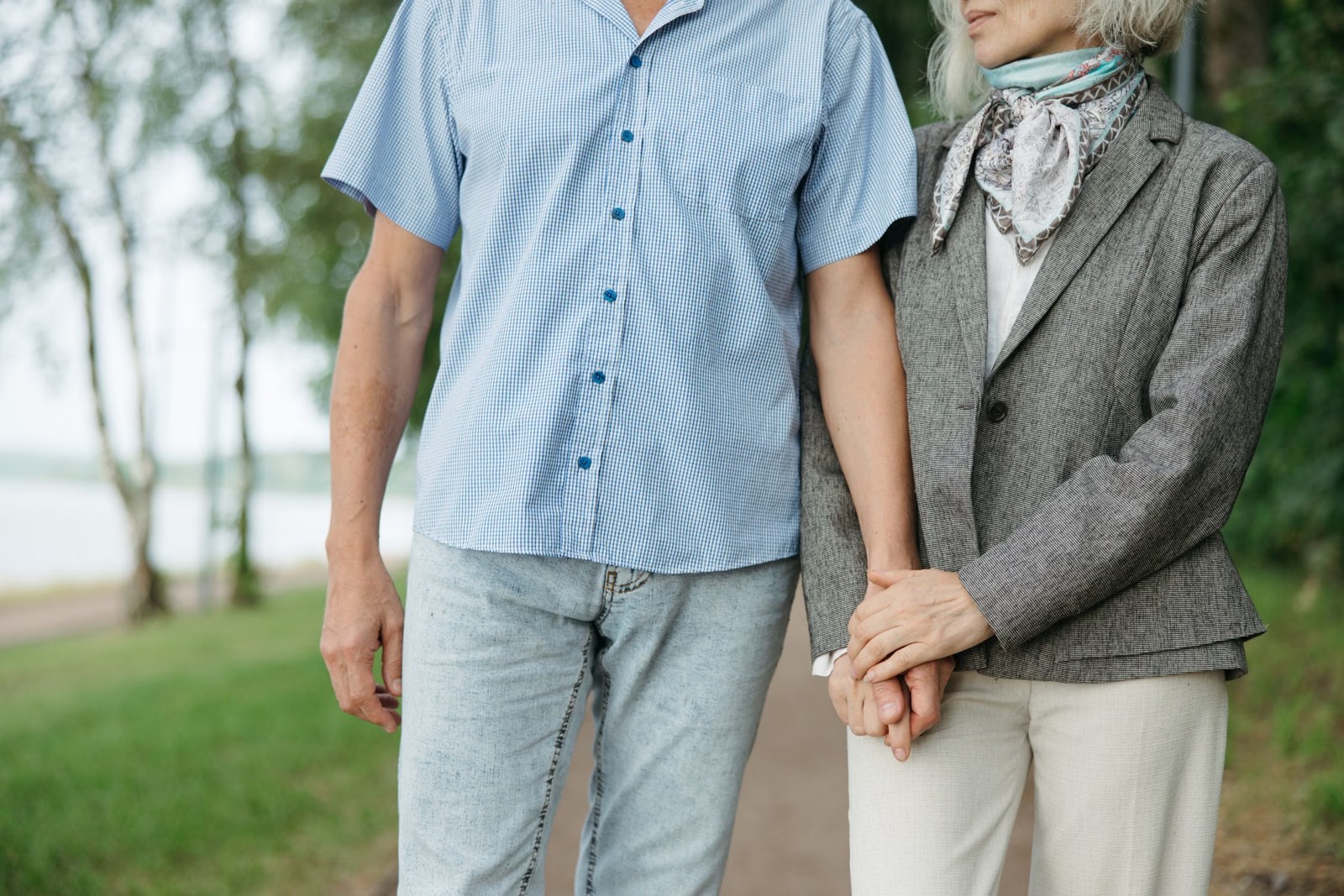 Un couple senior marche ensemble dans un parc, dans des tons bleu grisé et vert doux